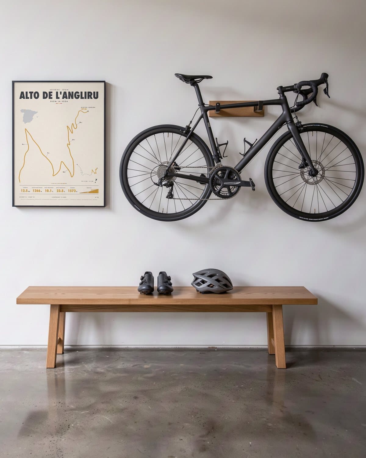 Alto de L'Angliru cycling climb poster in a black frame (45 × 60 cm) in a hallway beside a road bike
