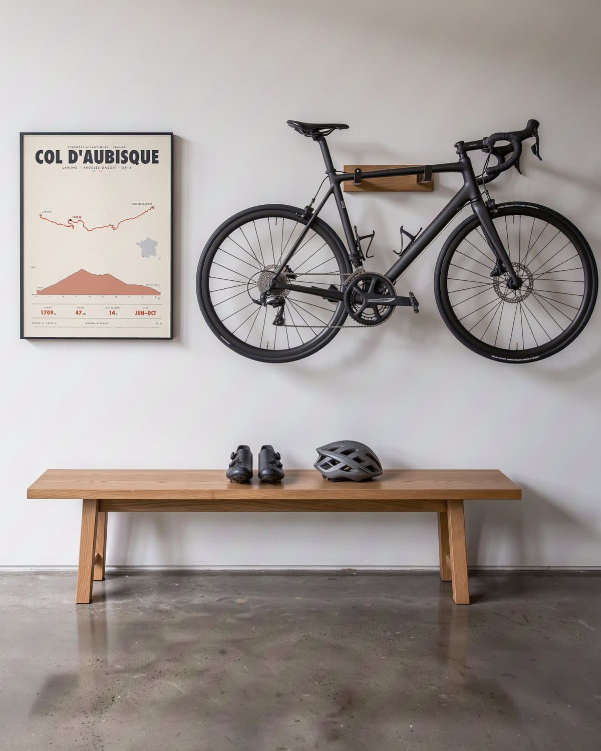 Col d'Aubisque mountain pass poster in a black frame (45 × 60 cm) in a hallway beside a road bike