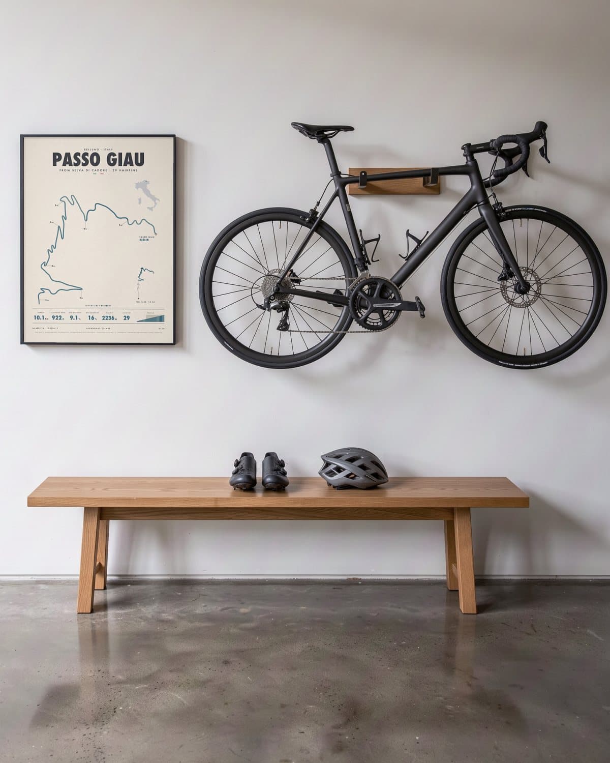 Passo Giau cycling climb poster in a black frame (45 × 60 cm) in a hallway beside a road bike