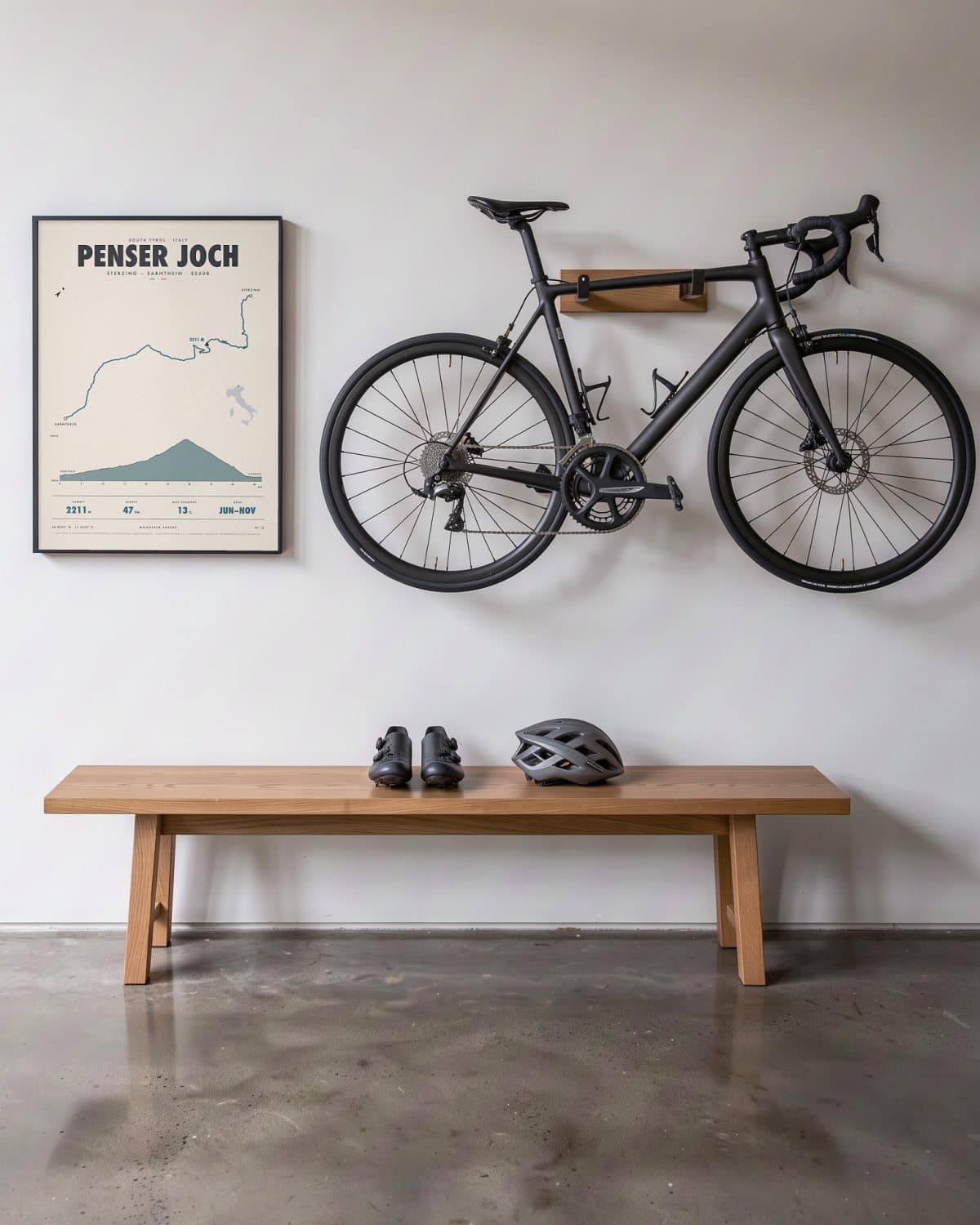 Penser Joch bergpasposter in een zwarte lijst (45 × 60 cm) in een hal naast een racefiets